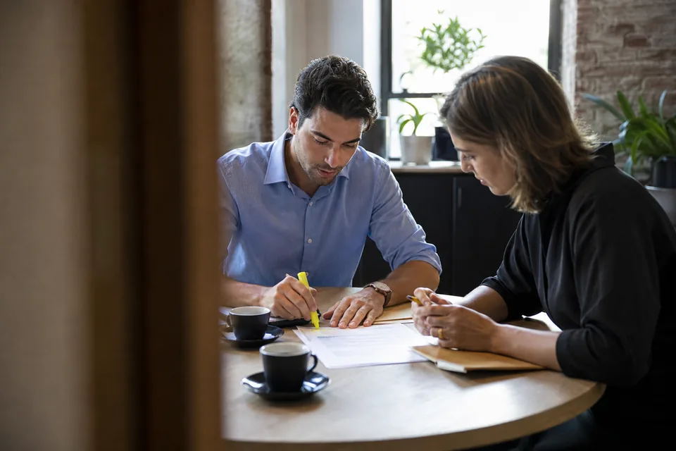 Two colleagues reviewing a contract renewal printout at a small meeting table